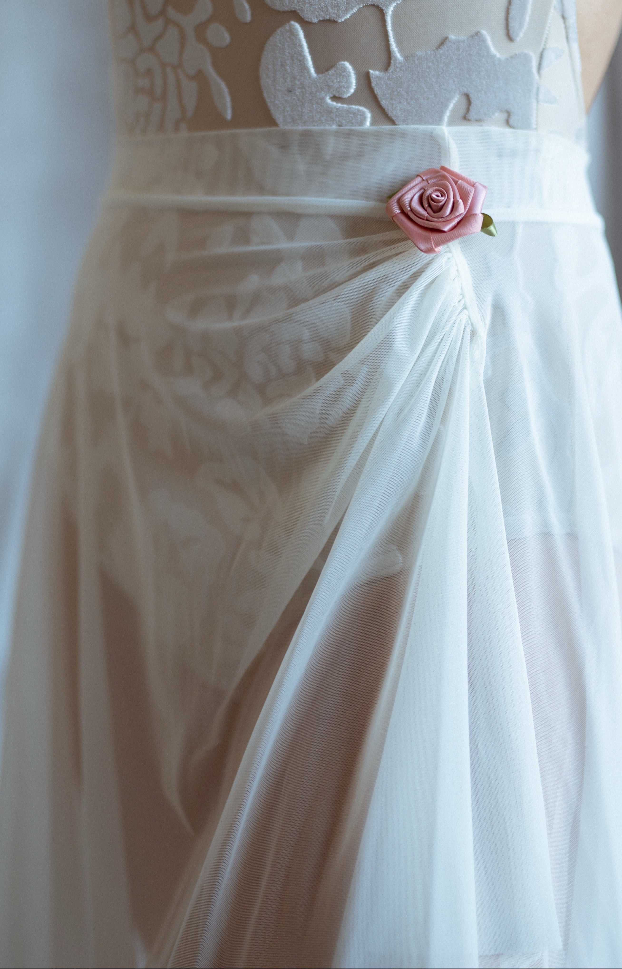 White mesh ballet skirt with a pink flower detail on a white background