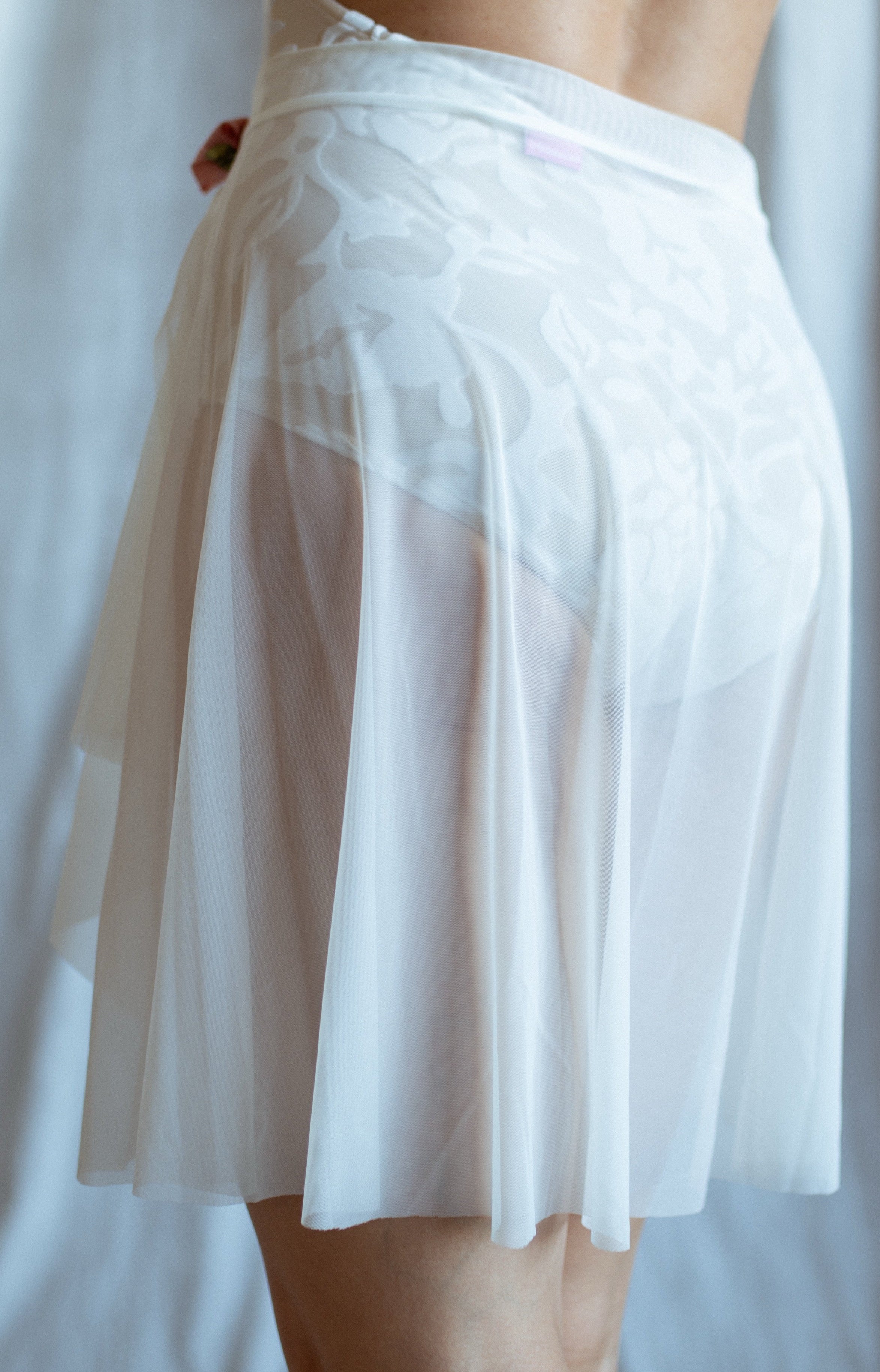 White sheer mesh skirt being worn by a person against a white background