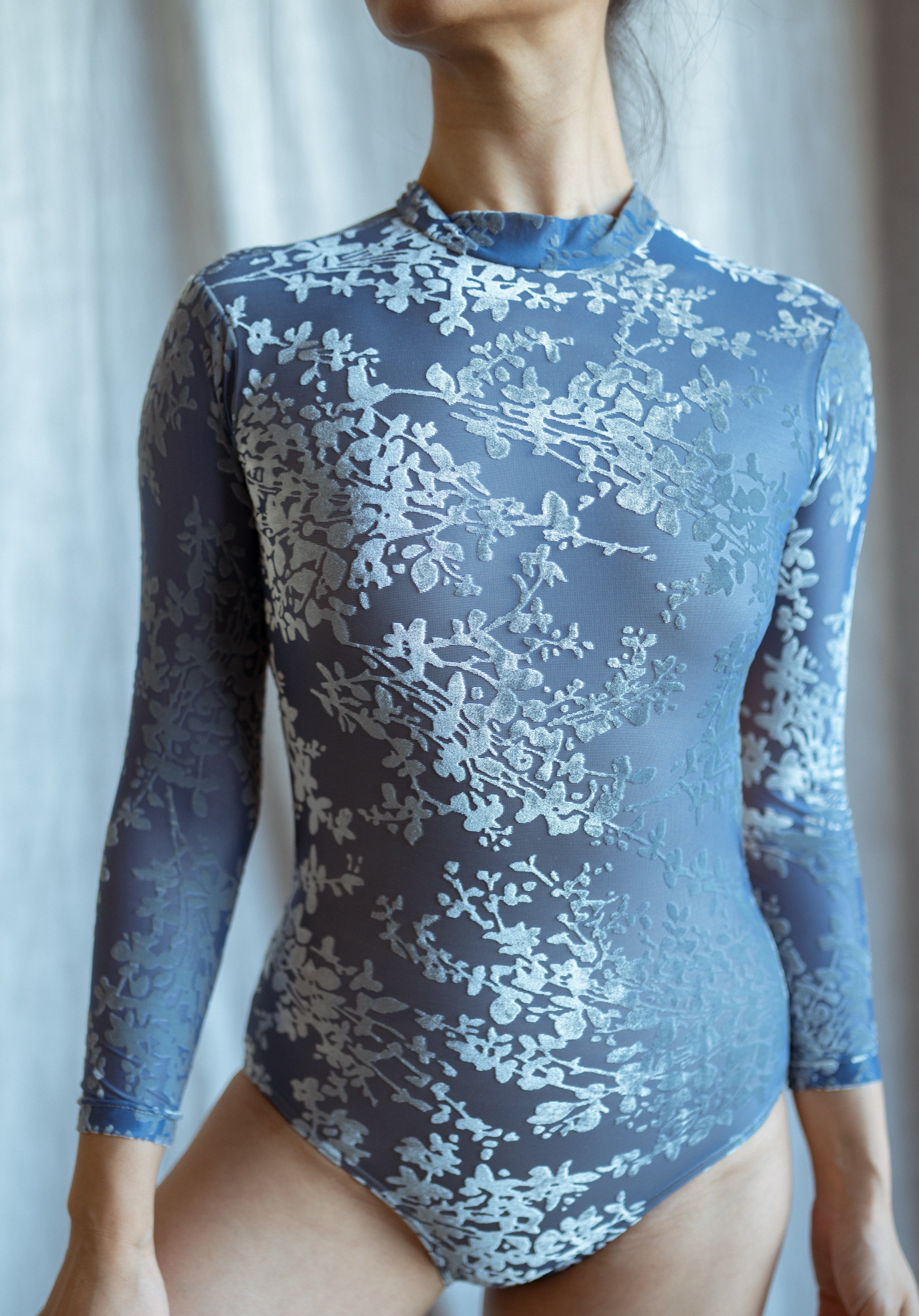 floral velvet bodysuit with long sleeves blue on a neutral background