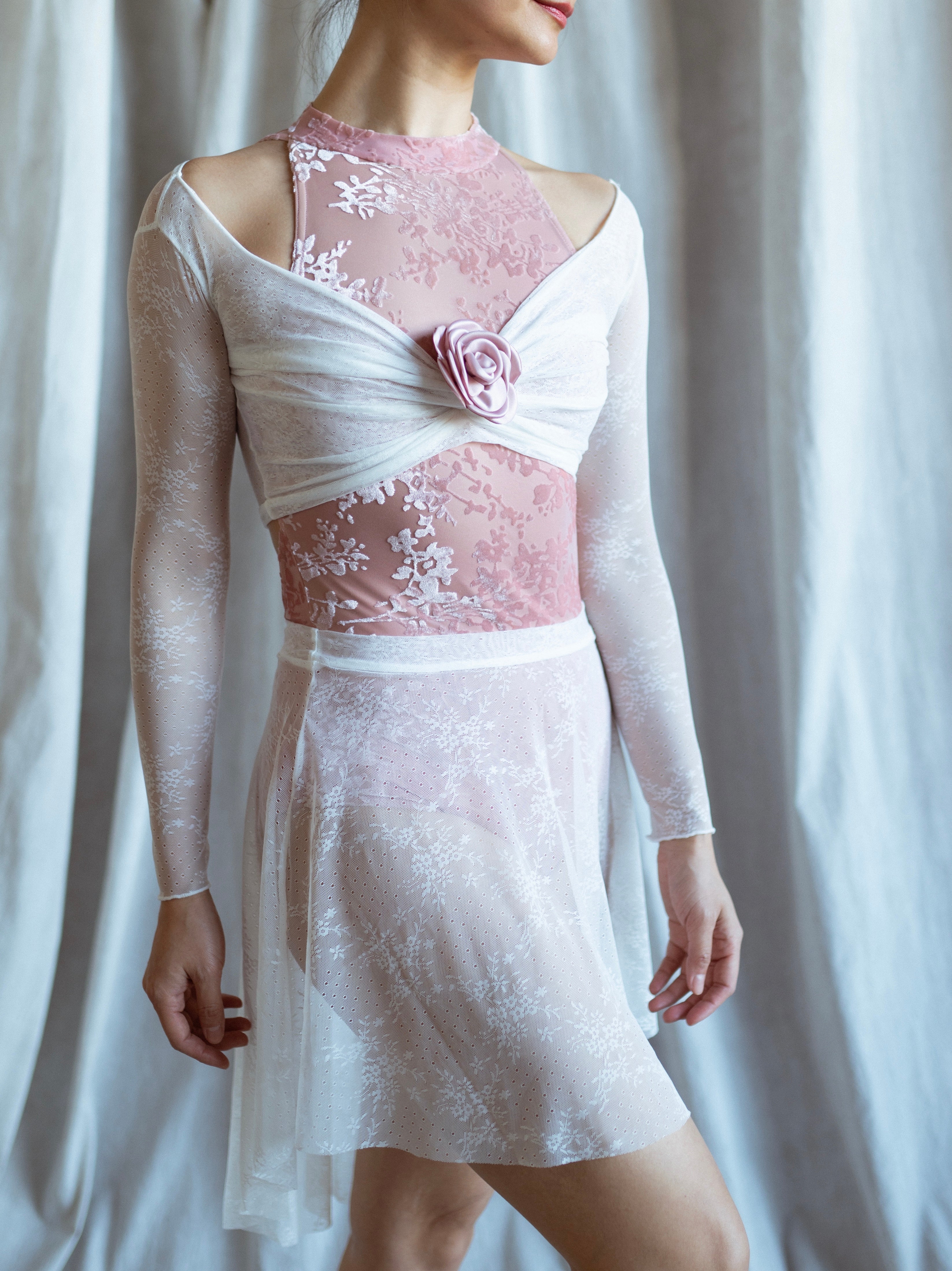 Lace warm up top with floral details and white lace skirt on a white background